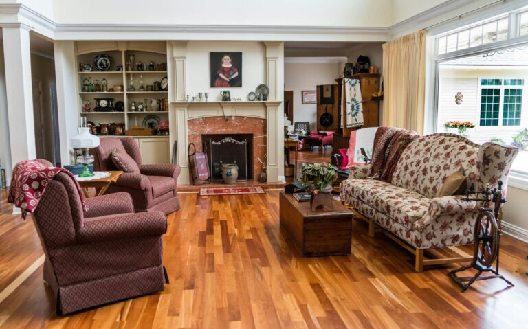 A spacious living room featuring floral patterned furniture, a fireplace, and wooden flooring.