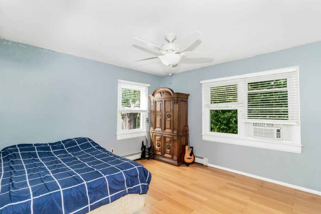 A bedroom featuring a blue wall, wooden furniture, and a guitar.